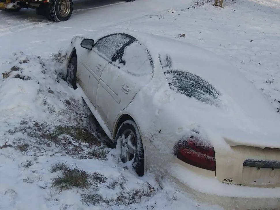 Car in a snowy ditch awaiting winter recovery