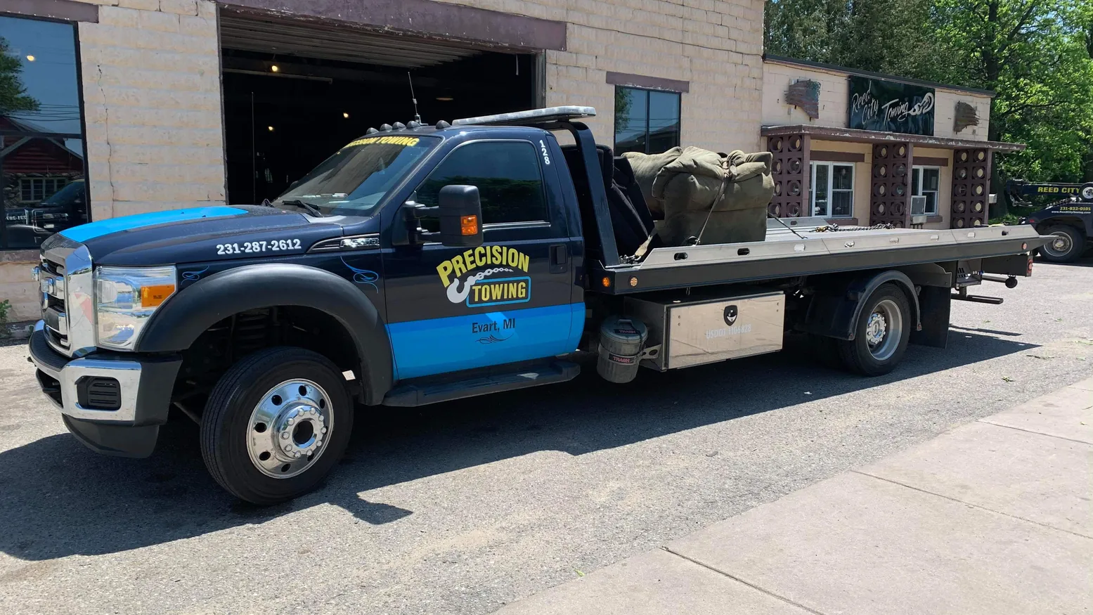 Precision Towing rollback in front of the Evart shop