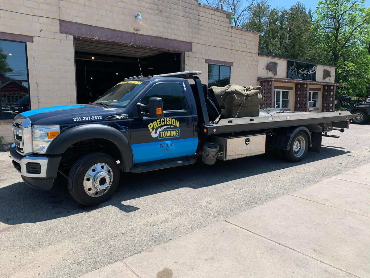 Precision Towing rollback tow truck outside the Evart, MI shop