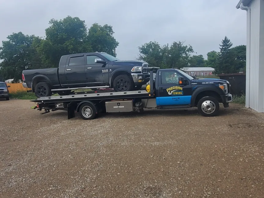 Precision Towing rollback with a car loaded on a gravel road